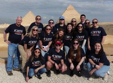 在2023年1月的埃及之旅中，穿着Utica t恤的学生和教师站在金字塔前.